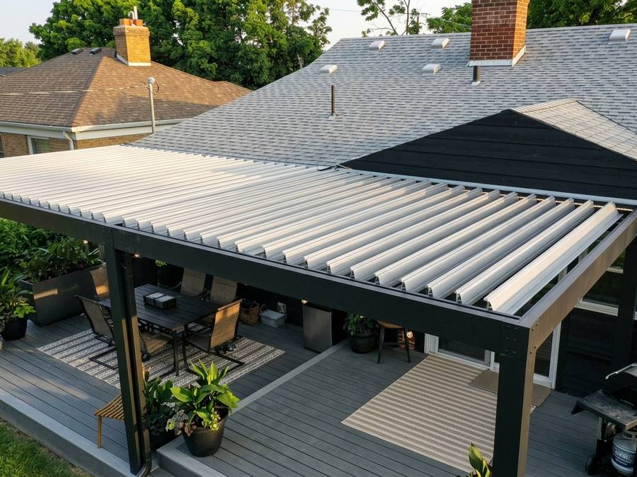Matte black pergola frame with white louvers over a deck and grill area