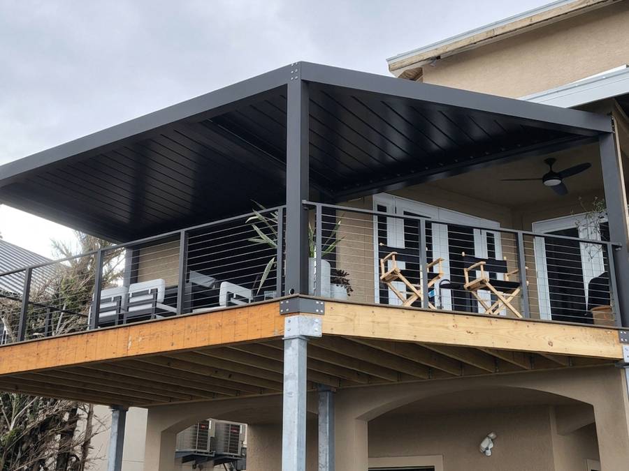 Matte black louvered pergola mounted off a second storey and cantilevered over the deck below